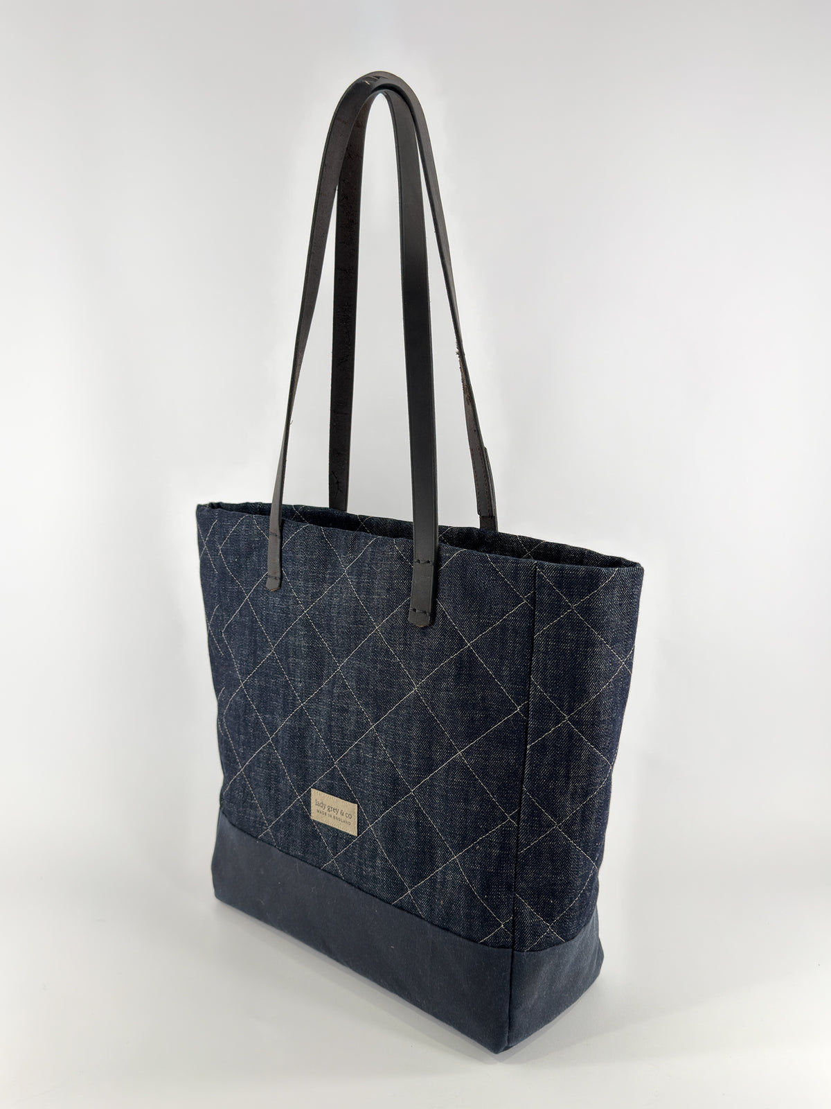 Denim tote bag with black handles on a white background